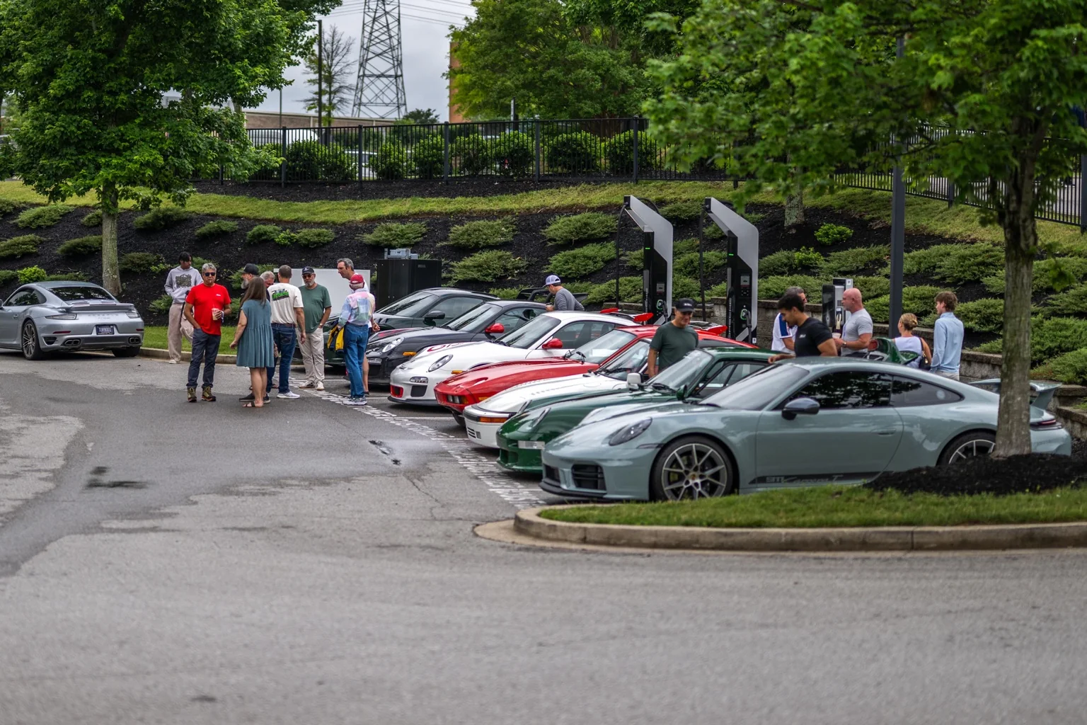 Car enthusiasts talking beside a lineup of Porsche sports cars at a meet